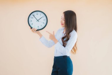 Güzel Asyalı genç bir kadının portresi izole edilmiş renk arkaplanında alarm ya da saati gösterir