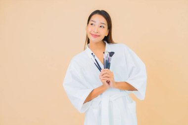 Renkli arka planda makyaj fırçası olan güzel bir Asyalı kadın portresi.