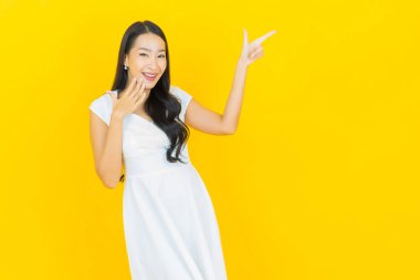 Asyalı güzel bir kadının portresi. Sarı arka planda hareketli gülümsüyor.