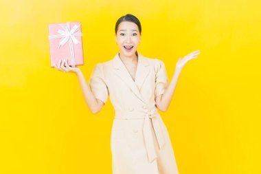 Güzel bir Asyalı kadının portresi. Arka planda kırmızı hediye kutusuyla gülümsüyor.