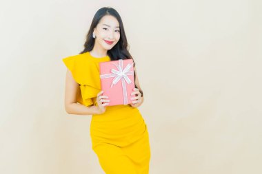 Güzel bir Asyalı kadının portresi. Arka planda kırmızı hediye kutusuyla gülümsüyor.