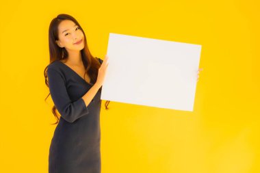 Sarı izole edilmiş arka planda boş ve boş ilan panosuyla güzel bir Asyalı kadın portresi.