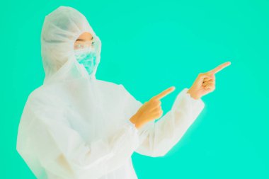 Güzel, genç Asyalı doktor kadın portre. Koronavirüsten ya da mavi arka planda kovid19 'dan korunmak için ppe ya da kişisel koruyucu ekipman takıyor.