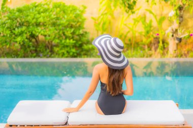 Güzel bir Asyalı kadının portresi tatil için yüzme havuzunda rahatlıyor.