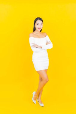 Portre güzel genç iş kadını gülümseyen ve eylem sarı arka planlı Asyalı kadın