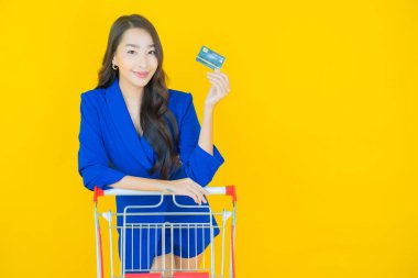 Renkli arka planda süpermarketten alınmış market sepetiyle gülümseyen güzel Asyalı kadın portresi.