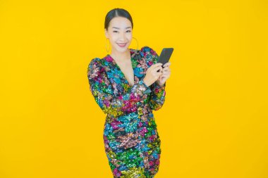 Renkli arka planda akıllı cep telefonuyla güzel Asyalı kadın gülümsemesi