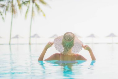 Güzel bir Asyalı kadın portresi. Tatil gezisinde deniz manzaralı açık havuz etrafında rahatça yüzebiliyor.