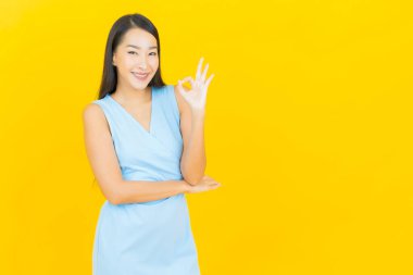 Asyalı güzel bir kadının portresi. Sarı arka planda hareketli gülümsüyor.