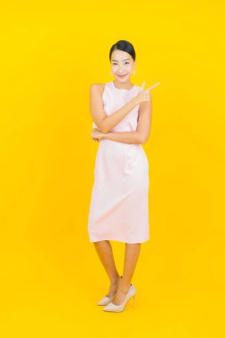 Asyalı güzel bir kadının portresi. Sarı arka planda hareketli gülümsüyor.