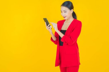 Renkli arka planda akıllı cep telefonuyla güzel Asyalı kadın gülümsemesi