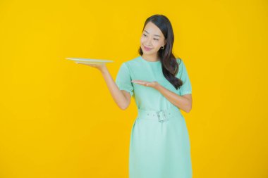 Güzel Asyalı bir kadının portresi. Arka planda boş tabak tabağıyla gülümsüyor.