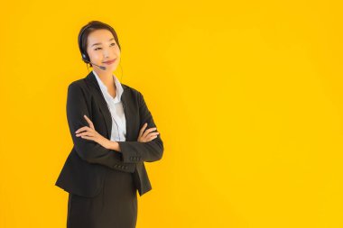 Portre güzel genç Asyalı kadın kulaklık ya da çağrı merkezi için kulaklık ya da tele pazarlama sarı izole arka planda.