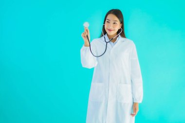 Klinikte ya da mavi izole edilmiş arka planda hastanede kullanmak üzere steteskoplu güzel Asyalı genç doktor kadın portresi.