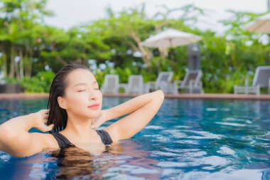 Güzel, genç Asyalı kadın portresi. Rahatlayın. Tatil için yüzme havuzunda gülümseyin.
