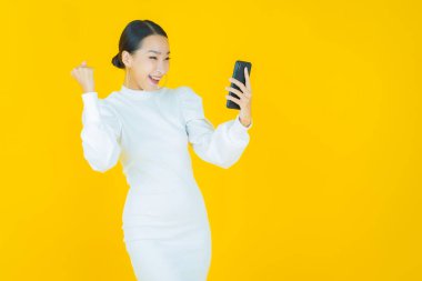 Renkli arka planda akıllı cep telefonuyla güzel Asyalı kadın gülümsemesi