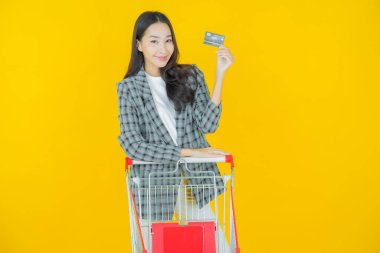 Renkli arka planda süpermarketten alınmış market sepetiyle gülümseyen güzel Asyalı kadın portresi.