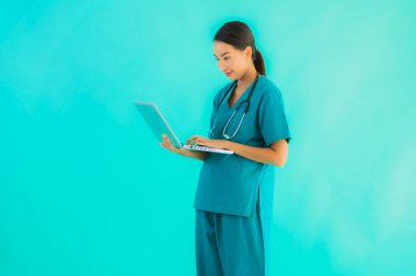 Mavi izole arka planda dizüstü bilgisayarı olan güzel Asyalı doktor kadın portresi.