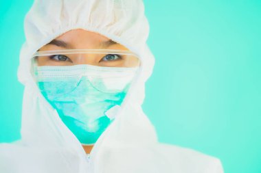 Güzel, genç Asyalı doktor kadın portre. Koronavirüsten ya da mavi arka planda kovid19 'dan korunmak için ppe ya da kişisel koruyucu ekipman takıyor.
