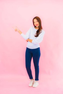 Portrait beautiful young asian woman smile with action on pink isolated background