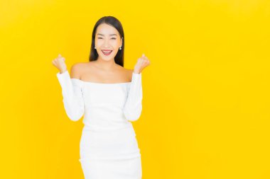 Portre güzel genç iş kadını gülümseyen ve eylem sarı arka planlı Asyalı kadın