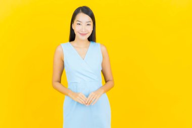 Asyalı güzel bir kadının portresi. Sarı arka planda hareketli gülümsüyor.