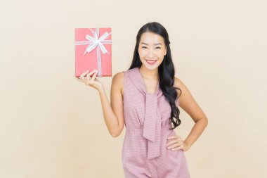 Güzel bir Asyalı kadının portresi. Arka planda kırmızı hediye kutusuyla gülümsüyor.