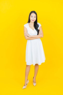 Asyalı güzel bir kadının portresi. Sarı arka planda hareketli gülümsüyor.