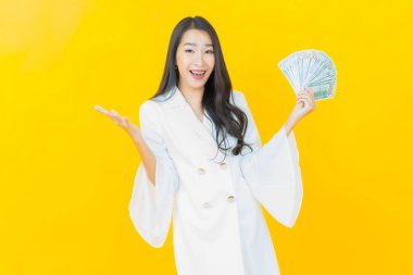 Asyalı güzel bir kadının portresi. Renkli arka planda bol para ve parayla gülümsüyor.