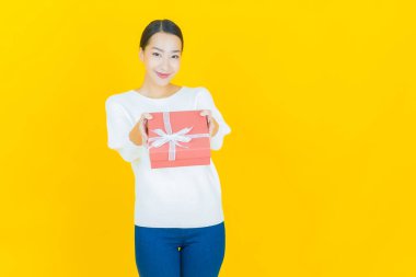 Güzel bir Asyalı kadının portresi. Arka planda kırmızı hediye kutusuyla gülümsüyor.