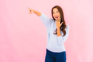 Portrait beautiful young asian woman smile with action on pink isolated background