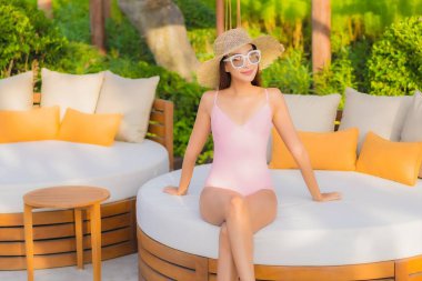 Güzel bir Asyalı kadın portresi. Tatil gezisinde deniz manzaralı açık havuz etrafında rahatça yüzebiliyor.