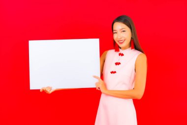 Güzel bir Asyalı kadın portresi kırmızı arka planda beyaz boş ilan panosu gösteriyor.