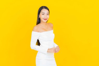 Portre güzel genç iş kadını gülümseyen ve eylem sarı arka planlı Asyalı kadın