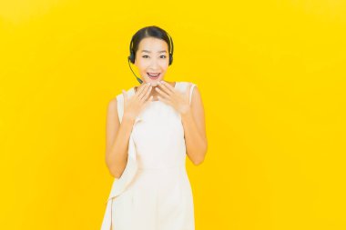 Sarı arka planda çağrı merkezi müşteri hizmetleri merkezi olan güzel Asyalı kadın portresi