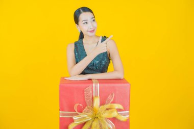 Güzel bir Asyalı kadının portresi. Arka planda kırmızı hediye kutusuyla gülümsüyor.