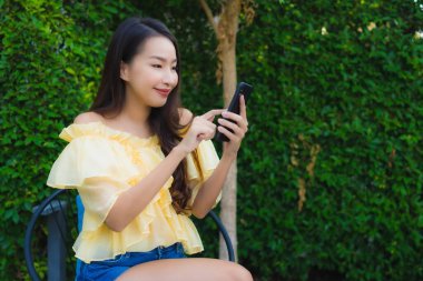 Genç Asyalı kadın açık hava manzarası için akıllı cep telefonu kullanıyor.