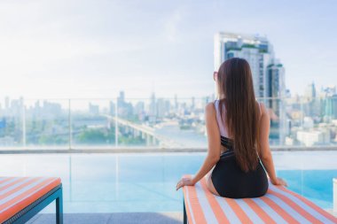 Güzel bir Asyalı kadının portresi tatil gezilerinde yüzme havuzunda rahatlar.