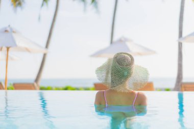 Güzel bir Asyalı kadın portresi. Tatil gezisinde deniz manzaralı açık havuz etrafında rahatça yüzebiliyor.