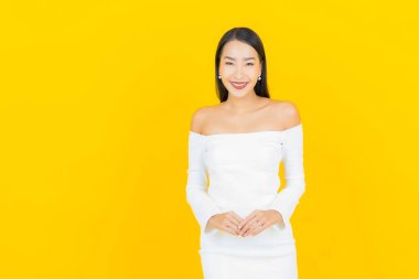 Portre güzel genç iş kadını gülümseyen ve eylem sarı arka planlı Asyalı kadın