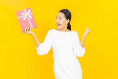 Güzel bir Asyalı kadının portresi. Arka planda kırmızı hediye kutusuyla gülümsüyor.