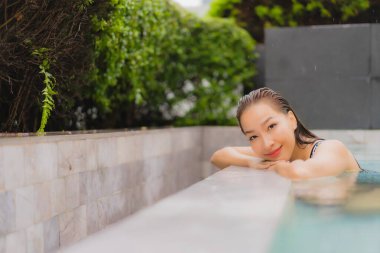Güzel bir Asyalı kadın portresi. Rahatlamak için açık havada yüzme havuzunda gülümse.