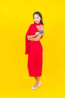 Sarı arka planda kredi kartı olan güzel bir Asyalı kadın portresi