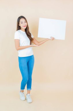 Güzel bir Asyalı kadın portresi. Krem arka planda boş beyaz ilan panosu kağıdı gösteriyor.