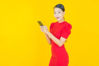 Renkli arka planda akıllı cep telefonuyla güzel Asyalı kadın gülümsemesi