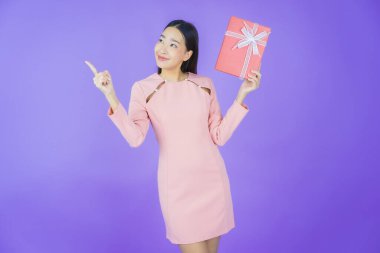 Güzel bir Asyalı kadının portresi. Arka planda kırmızı hediye kutusuyla gülümsüyor.