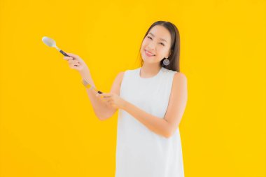 Sarı izole arka planda çatal kaşıklı güzel bir Asyalı kadın portresi.