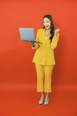Portre güzel genç iş kadını Asyalı kadın kırmızı arka planda bilgisayar bilgisayarı kullanıyor