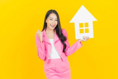 Sarı arka planda ev ya da kağıt tabelalı güzel Asyalı kadın portresi