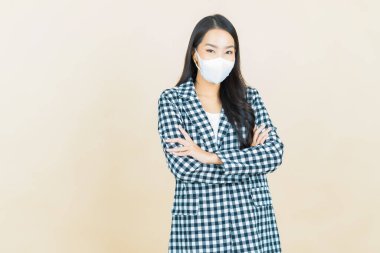 Sarı arka planda Covid19 veya virüsü korumak için maskeli güzel Asyalı kadın portresi